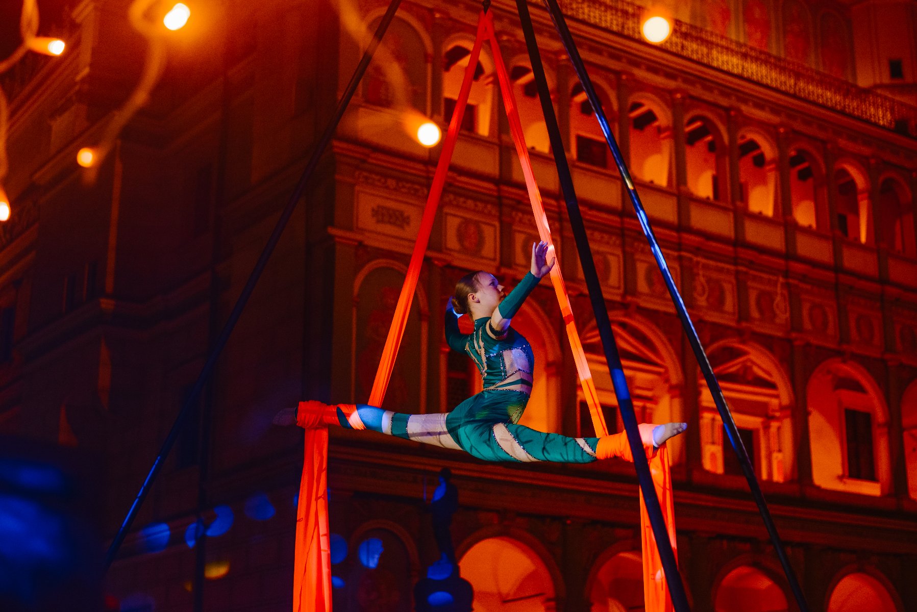 akrobatka wykonuje układ na szarfie na tle ratusza