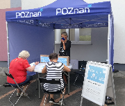 Dwie osoby wypełniają ankiety na stoisku konsultacji społecznych