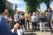 Grupa osób na chodniku przy domkach jednorodzinnych, z dwójką Strażników Miejskich.