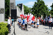 Młodzież z biało-czerwonymi flagami. Przed pomnikiem.