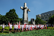 Młodzież z flagami Polski przed pomnikiem